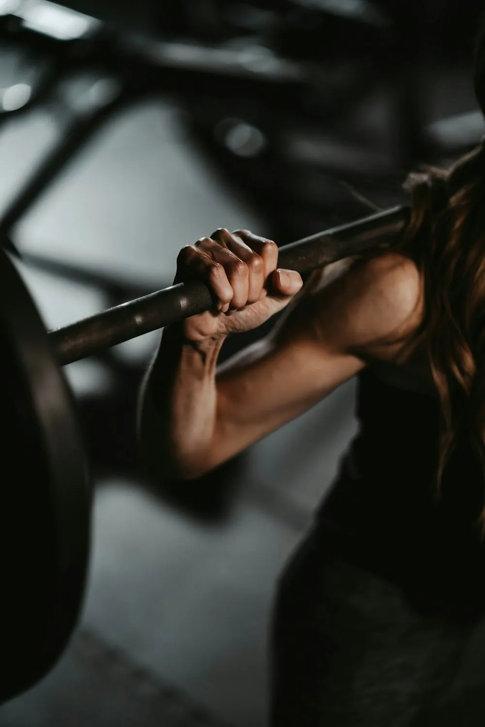 A lifter gripping a barbell across her shoulders in a close black and white shot
